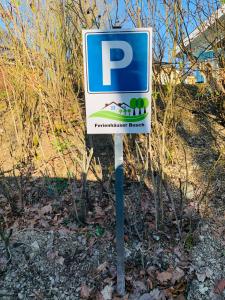 una señal de estacionamiento azul y blanco delante de algunos arbustos en Ferienpark - Komfort-Ferienhaus mitten in der Natur 5 Personen, en Extertal