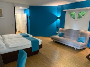 una camera da letto con pareti blu, un letto e un divano di Haus Villigst - Tagungsstätte der EKvW a Schwerte