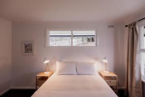 a bedroom with a large white bed with two lamps at Seaside home with nearby beach access in Taroona