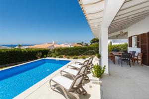 uma villa com uma piscina, uma mesa e cadeiras em Bini Sole - Villa de lujo con piscina en Menorca em Binibeca
