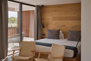 um quarto com uma cama e 2 cadeiras numa varanda em Las Gaviotas Suites Hotel & Spa em Playa de Muro