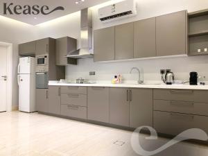 uma cozinha com armários cinzentos e um frigorífico branco em Kease Mughrizat C-6 Royal touch AX19 em Riyadh