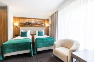 um quarto de hotel com duas camas e uma cadeira em Hotel Villa Verde Congress & Spa em Zawiercie Nowe