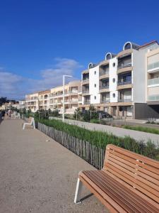 a wooden bench sitting on a sidewalk in front of buildings at Cap sur l'océan in Saint-Brevin-les-Pins