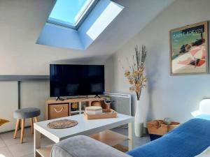 a living room with a flat screen tv and a table at Cap sur l'océan in Saint-Brevin-les-Pins