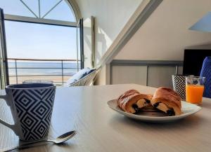 a plate of bread on a table with a cup of orange juice at Cap sur l'océan in Saint-Brevin-les-Pins