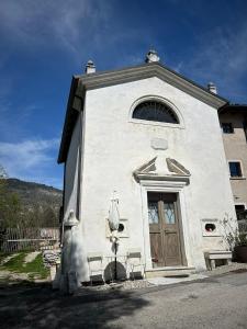 een kleine witte kerk met een deur en twee stoelen bij HOLLIDAY CHARMING HOME in Trento