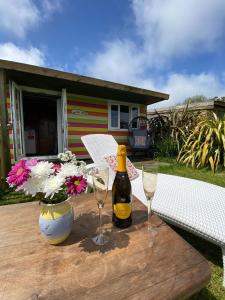 a bottle of wine and two glasses on a wooden table at Sunrise Cabin in Carbis Bay