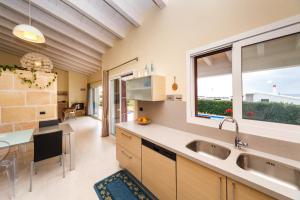 a kitchen with a large window and a sink at Bini Sole - Villa de lujo con piscina en Menorca in Binibeca
