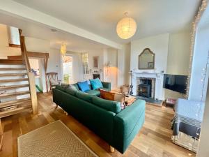 a living room with a green couch and a fireplace at 3 bedroom stunning house with garden and amazing sea views in Dartmouth