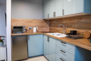 een keuken met blauwe kasten, een wastafel en een magnetron bij Novinea Apartamenty 