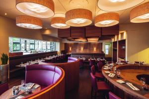 a restaurant with long tables and purple chairs at Mövenpick Hotel Zürich-Regensdorf in Regensdorf