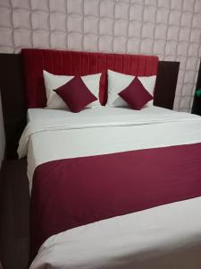 Cama roja y blanca con almohadas rojas y blancas en Erin Int Hotel en Sungguminasa