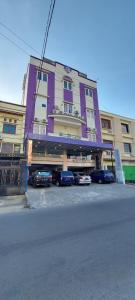 Sungguminasa的住宿－Erin Int Hotel，一座紫色的建筑,前面有汽车停放