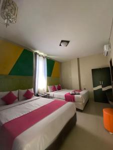2 łóżka w pokoju hotelowym z kolorowymi ścianami w obiekcie Erin Int Hotel w mieście Sungguminasa