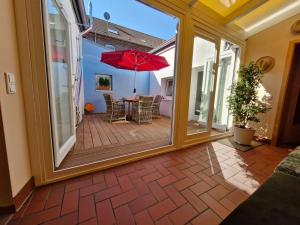 een patio met een tafel met een rode parasol bij Diana's Stube in Krefeld