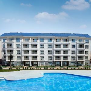 een appartementencomplex met een zwembad ervoor bij Azur One Eleven Hotel Alamein in El Alamein