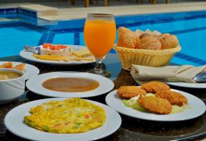 stół z talerzami jedzenia i szklanką soku pomarańczowego w obiekcie Azur One Eleven Hotel Alamein w mieście El Alamein