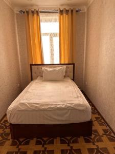 Una cama en una habitación pequeña con ventana. en Apartment in the city center, en Samarkand 1 foto más