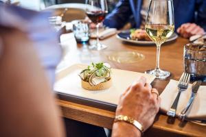 una persona sentada en una mesa con un plato de comida y vino en Hotel Atlantic Hamburg, Autograph Collection en Hamburgo