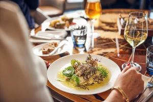 a table with a plate of food and glasses of wine at Hotel Atlantic Hamburg, Autograph Collection in Hamburg