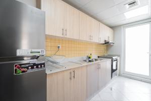 a kitchen with a stainless steel refrigerator and a sink at Nasma Luxury Stays - Luxurious Coastal Living Bab Al Bahr Residences in Ras al Khaimah