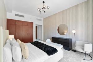 a bedroom with a large white bed and a chair at Nasma Luxury Stays - Luxurious Coastal Living Bab Al Bahr Residences in Ras al Khaimah