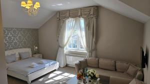 a bedroom with a bed and a couch and a window at Hotel nad Pilicą in Przedbórz