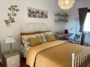Un dormitorio con una cama con sábanas amarillas y una lámpara de araña. en Casa Mimosa Holiday Room en Sperlonga