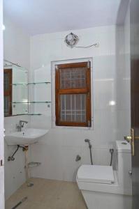 baño con aseo y lavabo y ventana en Colonel's Cottage, en Jaipur