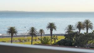 een uitzicht op een strand met palmbomen en de oceaan bij Six On N Apartments - Managed by Propr in Kaapstad