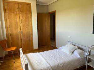 a bedroom with a white bed and a wooden cabinet at Apartamento Club de Golf León in León
