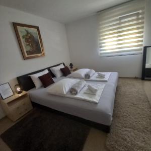 a bedroom with a large white bed with a window at Apartments Platz in Mostar