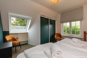 een slaapkamer met een groot bed en 2 ramen bij Vakantiehuis Zeepeertje, Vroondijk in Vrouwenpolder in Vrouwenpolder