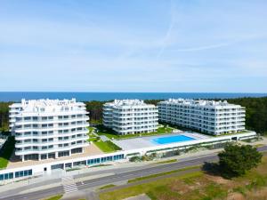 an aerial view of two white buildings and the ocean at Rogowo Pearl City Apartments in Rogowo