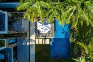 einen Blick über einen Pool mit einer Palme in der Unterkunft New World Phu Quoc Resort in Phu Quoc