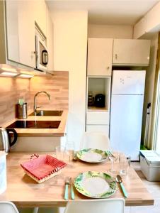 a kitchen with a table with plates and glasses on it at Studio soleil plage in Deauville +10 photos