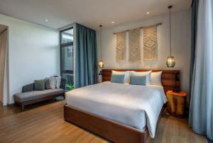 - une chambre avec un grand lit blanc et un canapé dans l'établissement New World Phu Quoc Resort, à Duong Dong