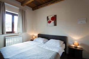 a bedroom with a bed with white sheets and a window at Guest House Valentincic in Nova Gorica