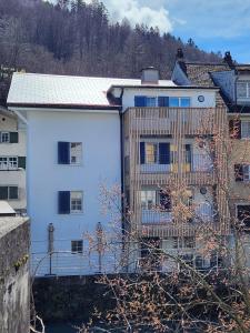 Ein weißes Gebäude mit einem Zaun davor. in der Unterkunft Spacious cellar studio surrounded by mountains and lake in Schwändi