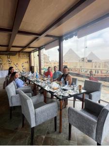 King Pyramids View Hotel في القاهرة: مجموعة من الناس يجلسون على طاولة في مطعم