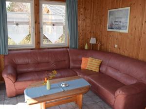 ein braunes Ledersofa im Wohnzimmer mit einem Tisch in der Unterkunft Komfort-Ferienhaus Wolke #56 in Extertal