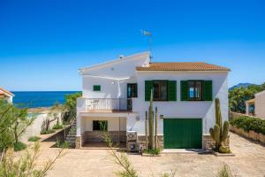 una casa bianca con un garage verde e l'oceano di Ran de Mar a Son Serra de Marina