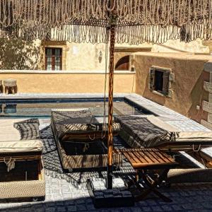 patio z 2 łóżkami i parasolem przy basenie w obiekcie Sclopa The Laography Project w mieście Kolimvari