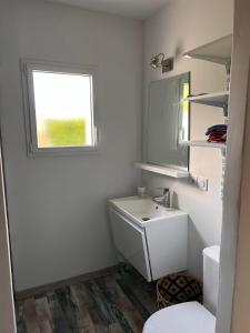 ein weißes Bad mit einem Waschbecken und einem Fenster in der Unterkunft Maison récente 3 chambres dont 1 suite parentale in Saint-Sauveur-dʼAunis