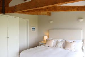 a bedroom with a white bed with white pillows at Clayhanger Lodge in Abbotsbury
