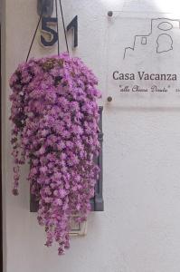 Ein Haufen lila Blumen hängt an der Wand in der Unterkunft Vacanza alla Chiesa Diruta in Grottole