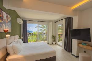 una camera con letto, TV e balcone di Morina Deluxe Hotel a Oludeniz