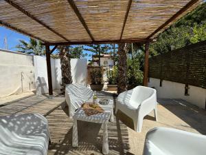 un patio con sillas blancas, una mesa y una pérgola en La Casa dell' Orso, en Santa Maria del Focallo