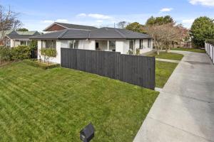 uma casa com uma cerca preta num quintal em Spacious Room Near Christchurch Airport em Christchurch